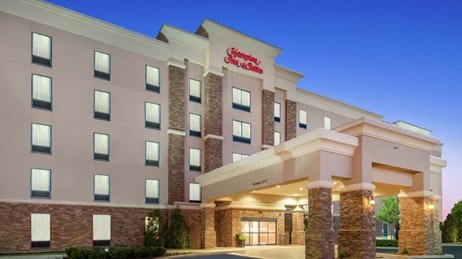 Five-story Hampton Inn building with a blue sky in the background